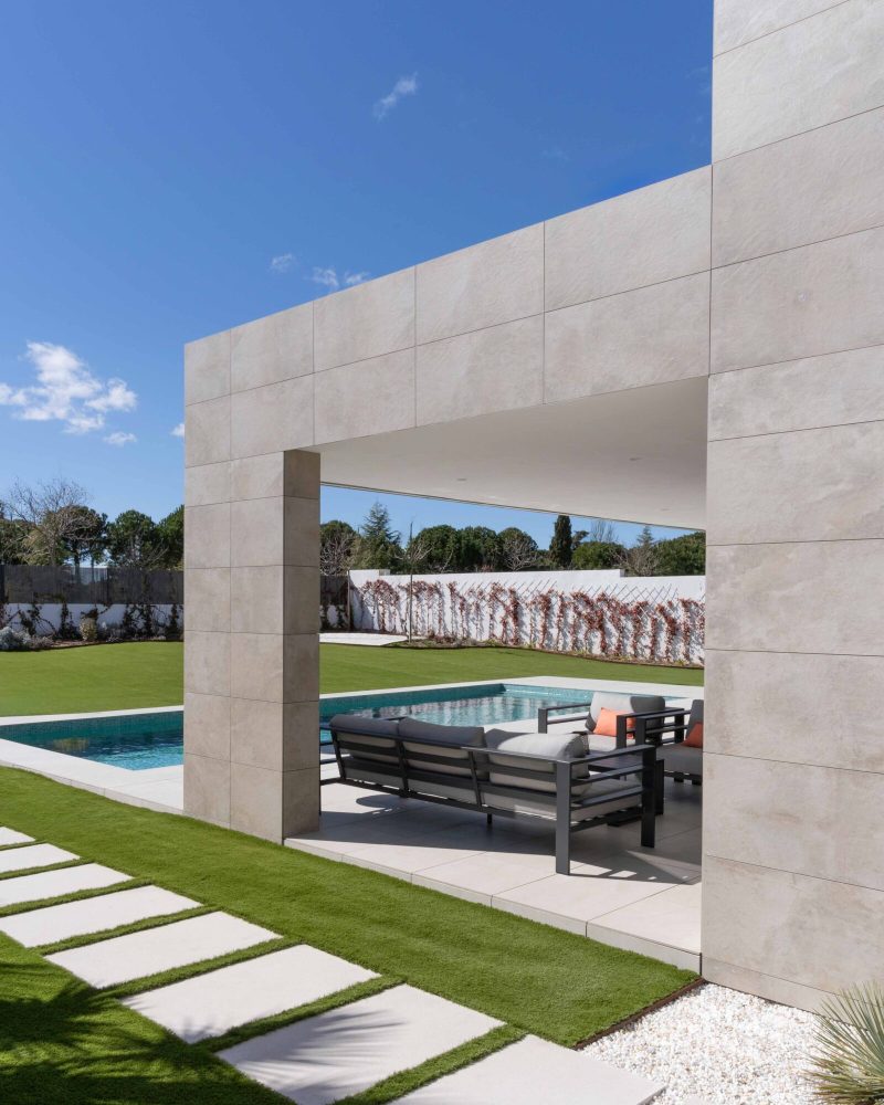 Garten und Swimmingpool eines hochwertigen Fertighauses in Madrid, Spanien. Seitenansicht.